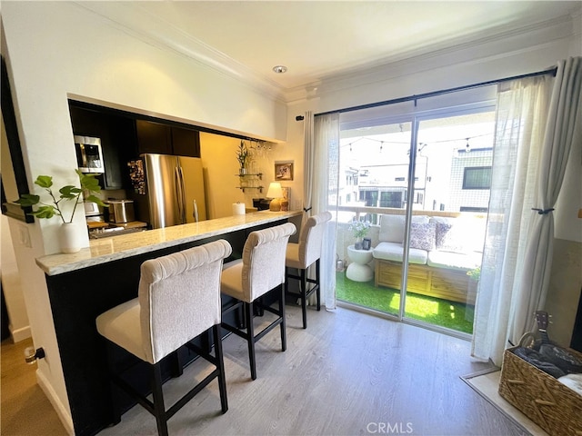 10960 Ashton Ave Unit 307, Los Angeles, CA 90024 - kitchen featuring freestanding refrigerator, ornamental molding, a kitchen bar, light wood-style flooring, and stove