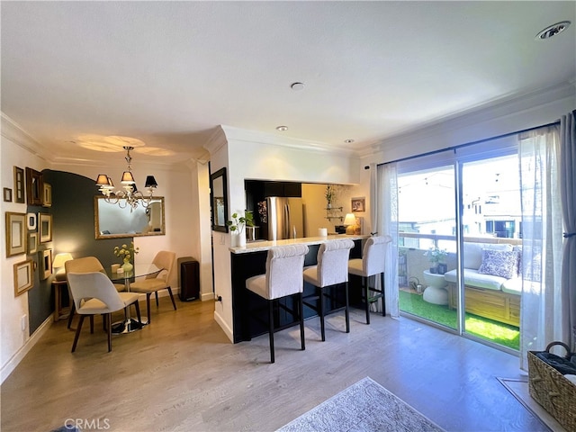 10960 Ashton Ave Unit 307, Los Angeles, CA 90024 - kitchen with freestanding refrigerator, crown molding, a chandelier, a breakfast bar area, and light wood-type flooring