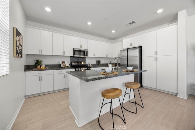 2544 Gunner Ridge Way, Rialto, CA 92377 - kitchen with appliances with stainless steel finishes, light wood-type flooring, white cabinets, a breakfast bar area, and recessed lighting