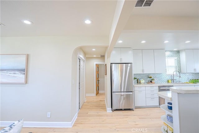 417 E 44th Way, Long Beach, CA 90807 - kitchen featuring freestanding refrigerator, light countertops, tasteful backsplash, arched walkways, and light wood-style floors