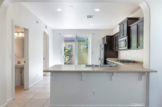 1587 N Strada Way, Clovis, CA 93619 - kitchen featuring arched walkways, a kitchen breakfast bar, stainless steel appliances, light countertops, and recessed lighting