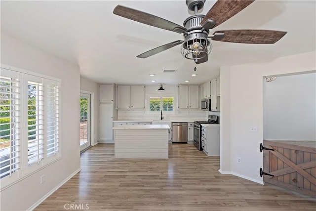 1825 Duncan Way, Corona, CA 92881 - kitchen with stainless steel appliances, a sink, a center island, light countertops, and baseboards