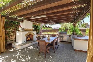 411 Snug Harbor Rd, Newport Beach, CA 92663 - view of patio with a lit fireplace, an outdoor kitchen, and outdoor dining area
