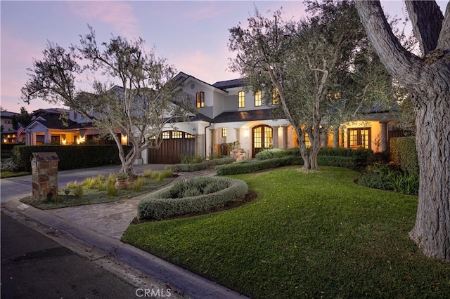411 Snug Harbor Rd, Newport Beach, CA 92663 - view of front of home with curved driveway, a yard, stucco siding, french doors, and a garage