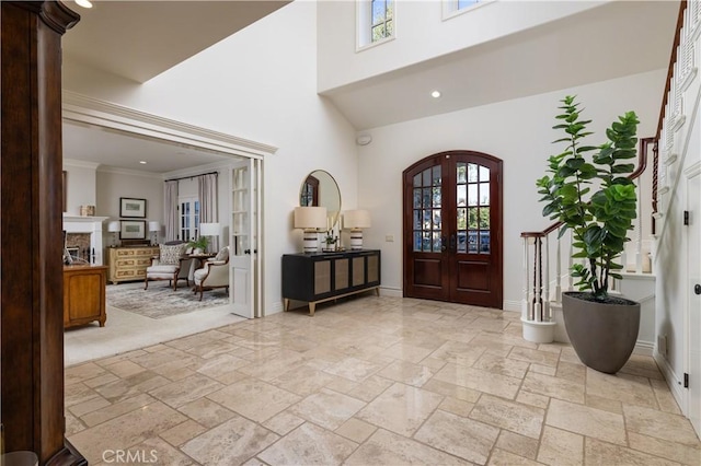 411 Snug Harbor Rd, Newport Beach, CA 92663 - entryway featuring french doors, a towering ceiling, stone tile flooring, baseboards, and a glass covered fireplace
