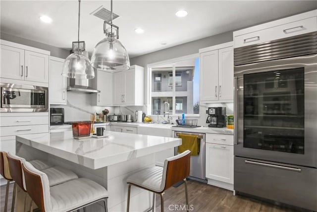 1639 Bridgewater Way, Costa Mesa, CA 92627 - kitchen with built in appliances, a sink, white cabinetry, light stone countertops, and a center island