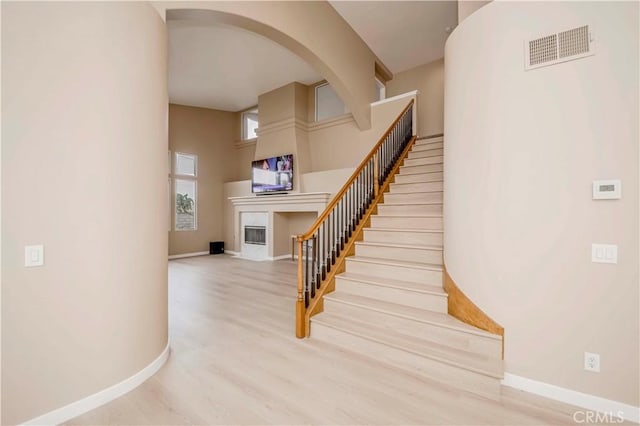 5338 S Chariton Ave, Ladera Heights, CA 90056 - staircase with a high end fireplace, baseboards, wood finished floors, a towering ceiling, and arched walkways