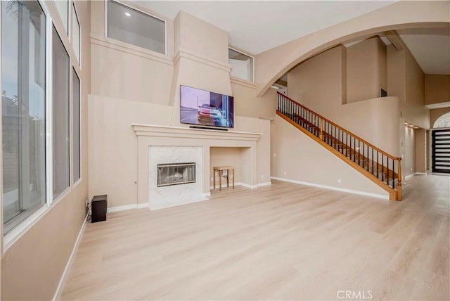 5338 S Chariton Ave, Ladera Heights, CA 90056 - unfurnished living room featuring wood finished floors, a towering ceiling, stairway, baseboards, and a premium fireplace