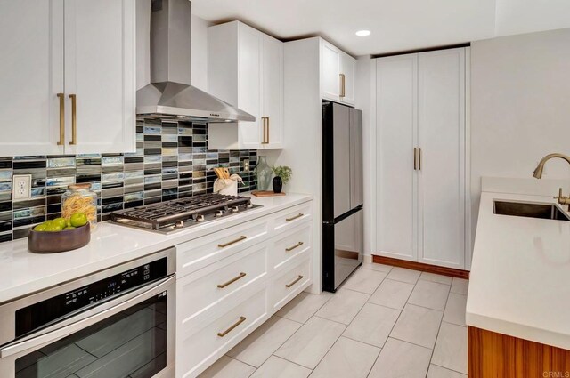 4103 Corral Canyon Rd, Bonita, CA 91902 - kitchen with wall chimney exhaust hood, appliances with stainless steel finishes, backsplash, light countertops, and white cabinetry