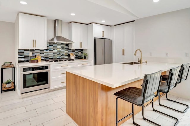 4103 Corral Canyon Rd, Bonita, CA 91902 - kitchen with stainless steel appliances, wall chimney range hood, a breakfast bar area, backsplash, and recessed lighting
