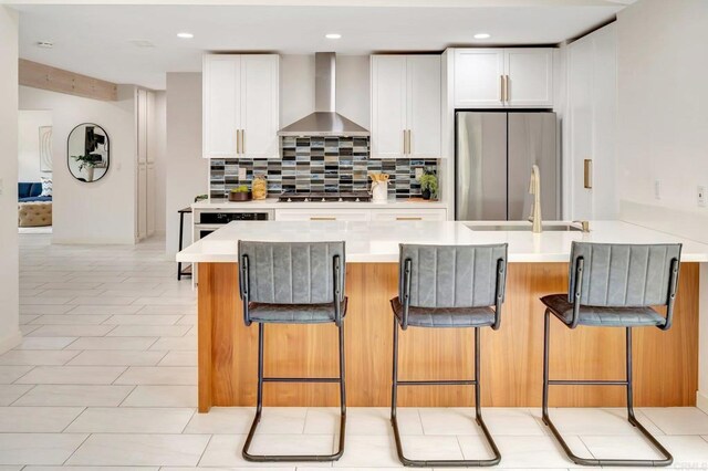 4103 Corral Canyon Rd, Bonita, CA 91902 - kitchen featuring wall chimney range hood, freestanding refrigerator, gas stovetop, backsplash, and a breakfast bar area