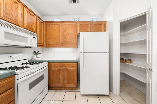 167 Iris Ln, Brea, CA 92821 - kitchen featuring white appliances, tile counters, light tile patterned flooring, and brown cabinetry