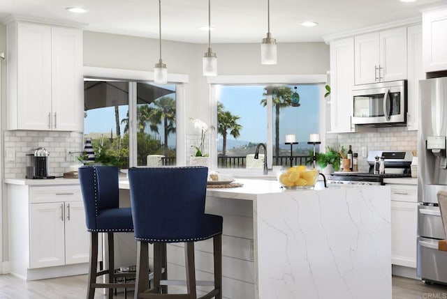 13356 Corte De Chucena, San Diego, CA 92128 - kitchen with appliances with stainless steel finishes, decorative backsplash, white cabinets, a breakfast bar area, and recessed lighting