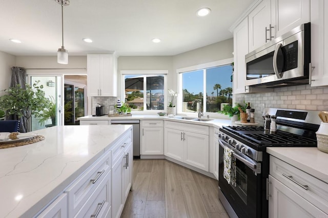 13356 Corte De Chucena, San Diego, CA 92128 - kitchen featuring stainless steel appliances, a sink, light wood finished floors, backsplash, and white cabinets
