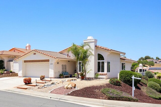 13356 Corte De Chucena, San Diego, CA 92128 - mediterranean / spanish-style house featuring a chimney, a tiled roof, an attached garage, and stucco siding