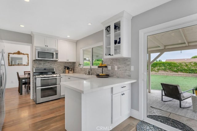 167 Camino Leon, Camarillo, CA 93012 - kitchen with stainless steel appliances, a peninsula, backsplash, light wood-style flooring, and white cabinets