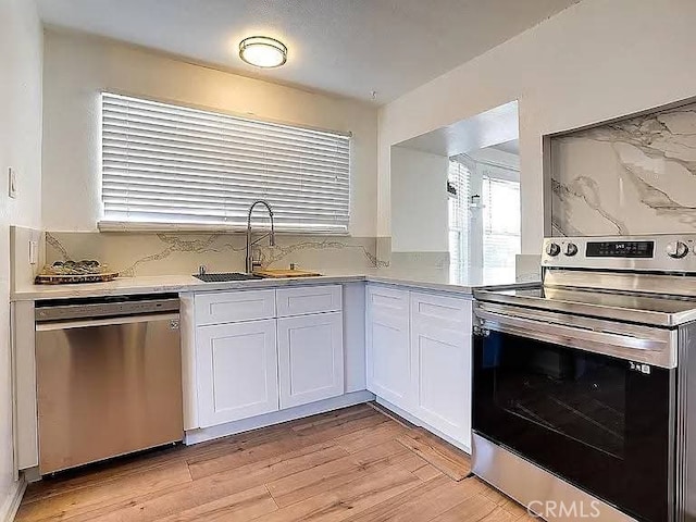 25 W Walnut St, Stockton, CA 95204 - kitchen with appliances with stainless steel finishes, a sink, white cabinetry, light countertops, and light wood finished floors