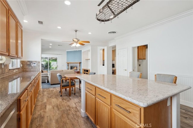 19613 Edmonds Pl, Saugus, CA 91350 - kitchen with wood finished floors, ceiling fan, ornamental molding, a warm lit fireplace, and a center island