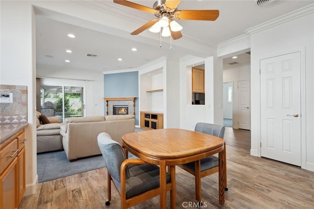 19613 Edmonds Pl, Saugus, CA 91350 - dining space featuring a lit fireplace, ornamental molding, recessed lighting, light wood finished floors, and a ceiling fan