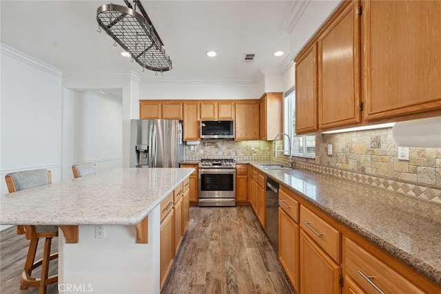 19613 Edmonds Pl, Saugus, CA 91350 - kitchen featuring stainless steel appliances, wood finished floors, crown molding, a kitchen breakfast bar, and light stone countertops