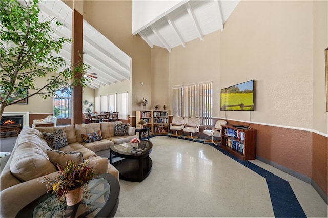 43195 Andrade Ave Unit L, Hemet, CA 92544 - living room featuring high vaulted ceiling, beamed ceiling, speckle patterned floor, a textured wall, and a warm lit fireplace