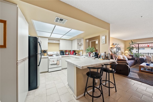 43195 Andrade Ave Unit L, Hemet, CA 92544 - kitchen with gas range gas stove, freestanding refrigerator, a peninsula, open floor plan, and tile counters