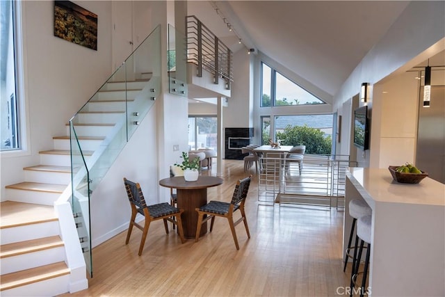 901 Summit Dr, Laguna Beach, CA 92651 - dining room with light wood-style floors, stairway, high vaulted ceiling, a fireplace, and track lighting