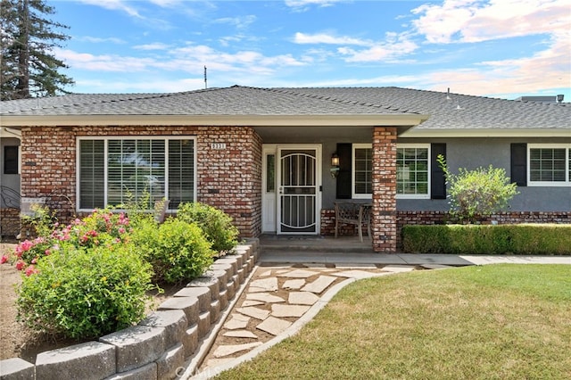 9331 E Mesa Ave, Clovis, CA 93619 - entrance to property featuring brick siding, covered porch, a yard, a shingled roof, and stucco siding