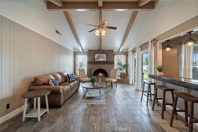 9331 E Mesa Ave, Clovis, CA 93619 - living room with dark wood-style flooring, a ceiling fan, a fireplace, beam ceiling, and wooden walls