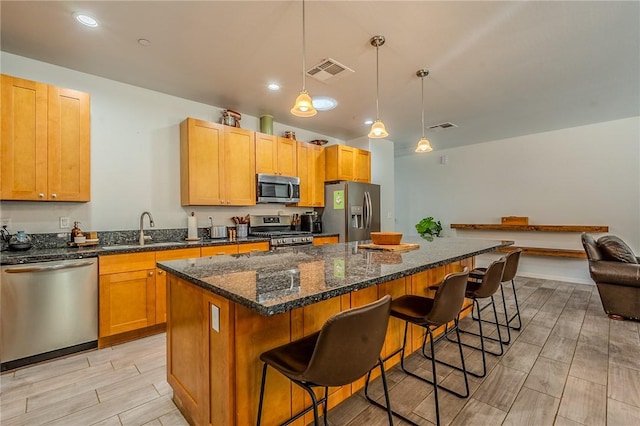 21604 Adam Dr, Tehachapi, CA 93561 - kitchen featuring stainless steel appliances, a sink, wood tiled floors, a kitchen island, and a breakfast bar