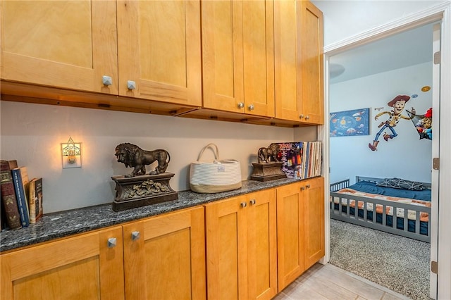 21604 Adam Dr, Tehachapi, CA 93561 - kitchen with dark stone counters, light carpet, and brown cabinetry