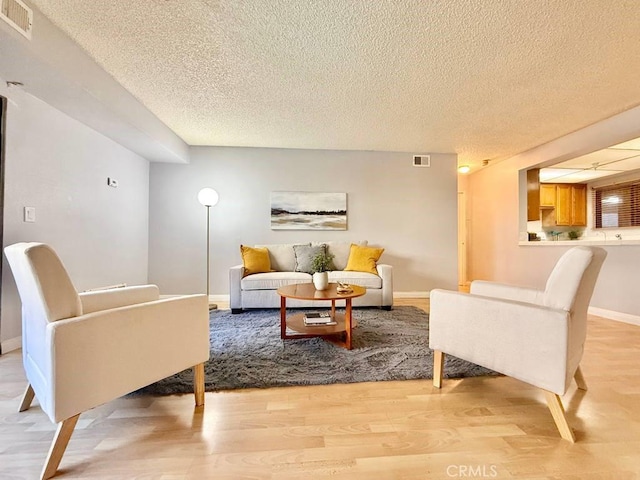 4142 E Mendez St Unit 132, Long Beach, CA 90815 - living area with a textured ceiling, light wood finished floors, and baseboards