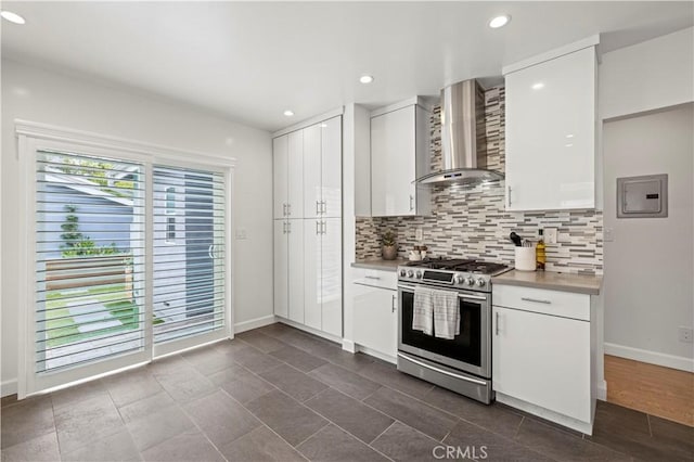 5834 Satsuma Ave, North Hollywood, CA 91601 - kitchen featuring stainless steel range with gas stovetop, wall chimney exhaust hood, white cabinetry, decorative backsplash, and baseboards