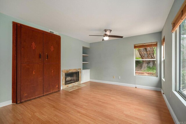513 Shadow Tree Dr, Oceanside, CA 92058 - unfurnished living room featuring light wood-style floors, a high end fireplace, ceiling fan, baseboards, and built in features
