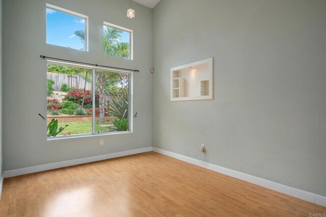 513 Shadow Tree Dr, Oceanside, CA 92058 - empty room featuring healthy amount of natural light, wood finished floors, a high ceiling, and baseboards