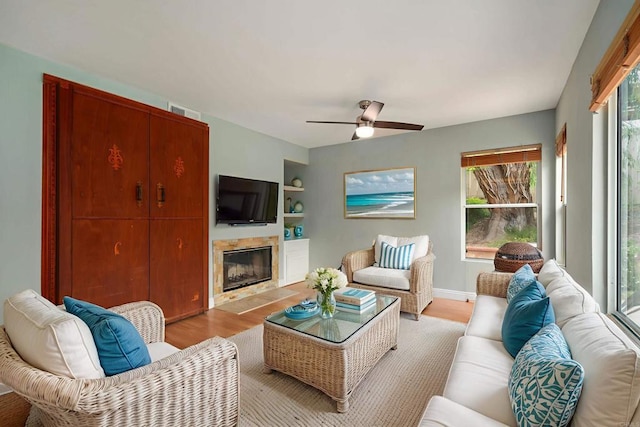 513 Shadow Tree Dr, Oceanside, CA 92058 - living room with light wood finished floors, a premium fireplace, a ceiling fan, built in features, and baseboards