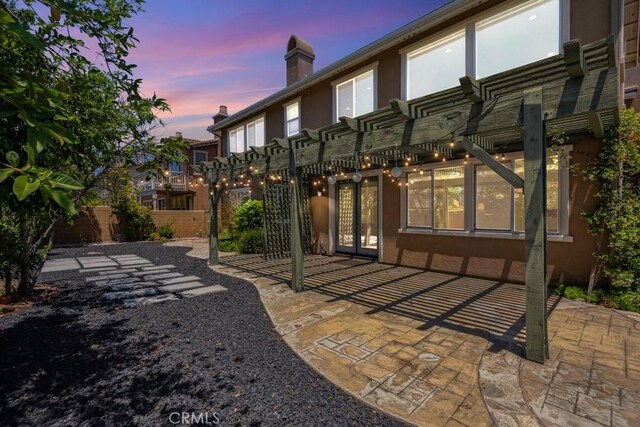 4224 Oliphant Ct, Riverside, CA 92505 - back of property at dusk featuring a pergola, a patio area, a chimney, and stucco siding