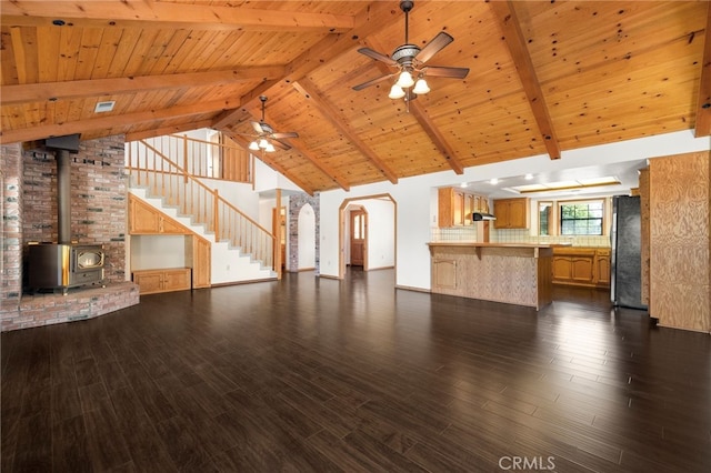 22635 Juanita Ct, Red Bluff, CA 96080 - unfurnished living room with wooden ceiling with exposed beams, ceiling fan, dark wood-style flooring, a wood stove, and arched walkways