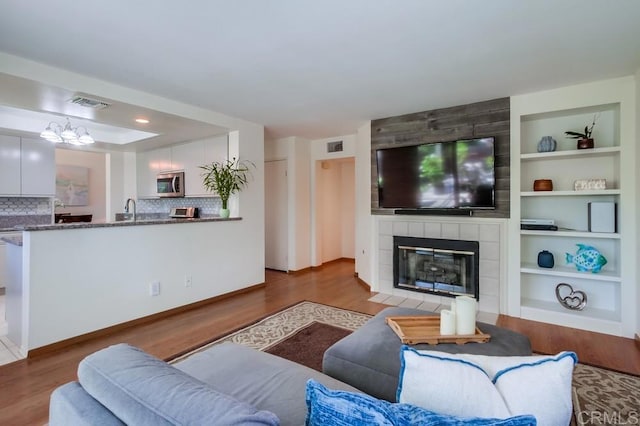 543 Boysenberry Way, Oceanside, CA 92057 - living room with wood finished floors, a tile fireplace, a chandelier, and built in features