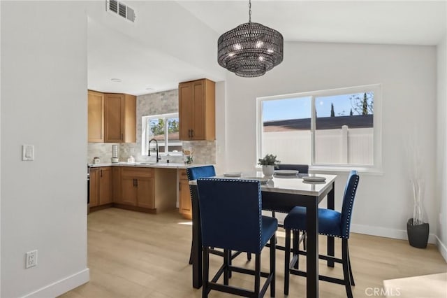 12548 Terra Bella St, Pacoima, CA 91331 - dining space with a chandelier, light wood-style floors, vaulted ceiling, and baseboards