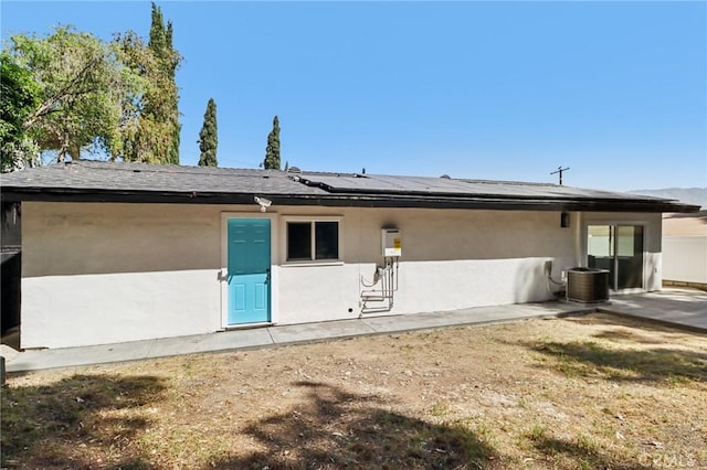 12548 Terra Bella St, Pacoima, CA 91331 - rear view of house featuring roof mounted solar panels, stucco siding, central AC, and a patio area