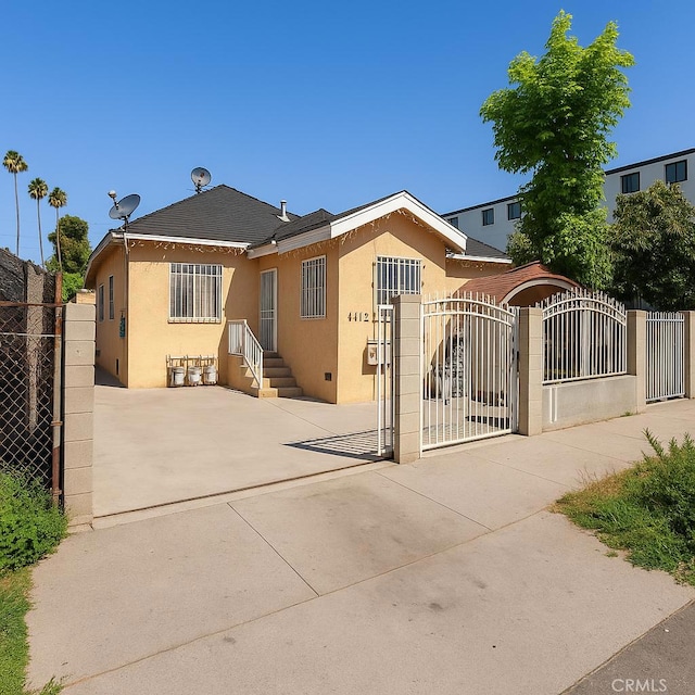 4415 Mettler St Unit 4413, Los Angeles, CA 90011 - view of front of property with stucco siding, a gate, a fenced front yard, and concrete driveway