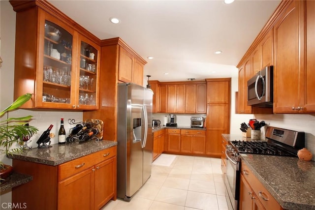 8630 Forsythe St, Sunland, CA 91040 - kitchen featuring appliances with stainless steel finishes, decorative backsplash, recessed lighting, dark stone counters, and glass insert cabinets