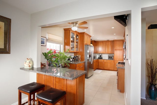 8630 Forsythe St, Sunland, CA 91040 - kitchen featuring stainless steel fridge, a peninsula, glass insert cabinets, dark stone counters, and a ceiling fan