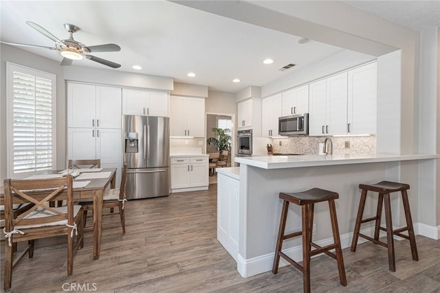 26121 Calle Cresta, Mission Viejo, CA 92692 - kitchen with appliances with stainless steel finishes, a peninsula, a ceiling fan, tasteful backsplash, and wood finished floors
