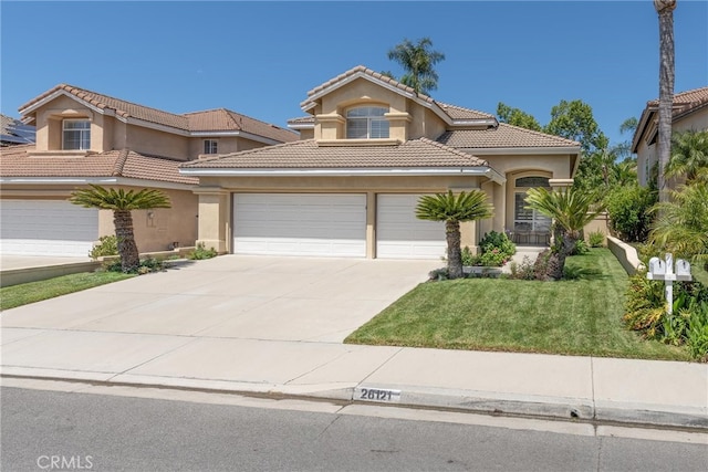 26121 Calle Cresta, Mission Viejo, CA 92692 - mediterranean / spanish home featuring concrete driveway, stucco siding, a tile roof, a front yard, and a garage