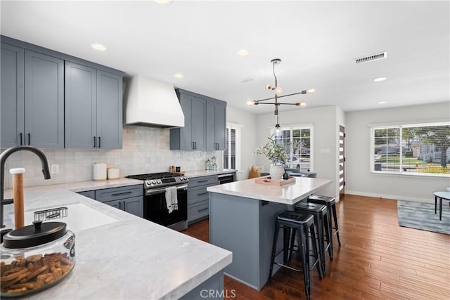 3409 W 175th St, Torrance, CA 90504 - kitchen featuring stainless steel gas range oven, custom range hood, a center island, a breakfast bar, and backsplash