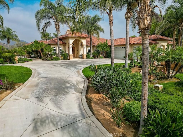 6116 Chadbourne Ave, Riverside, CA 92505 - mediterranean / spanish-style house with curved driveway, stucco siding, a tile roof, and an attached garage