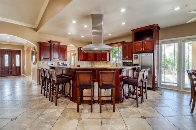 6116 Chadbourne Ave, Riverside, CA 92505 - kitchen featuring stainless steel appliances, island exhaust hood, arched walkways, reddish brown cabinets, and crown molding