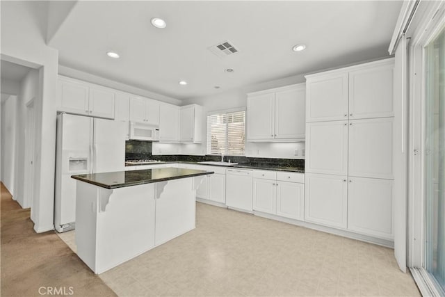 28538 Redwood Canyon Pl, Saugus, CA 91390 - kitchen with white appliances, a center island, a sink, white cabinets, and dark countertops